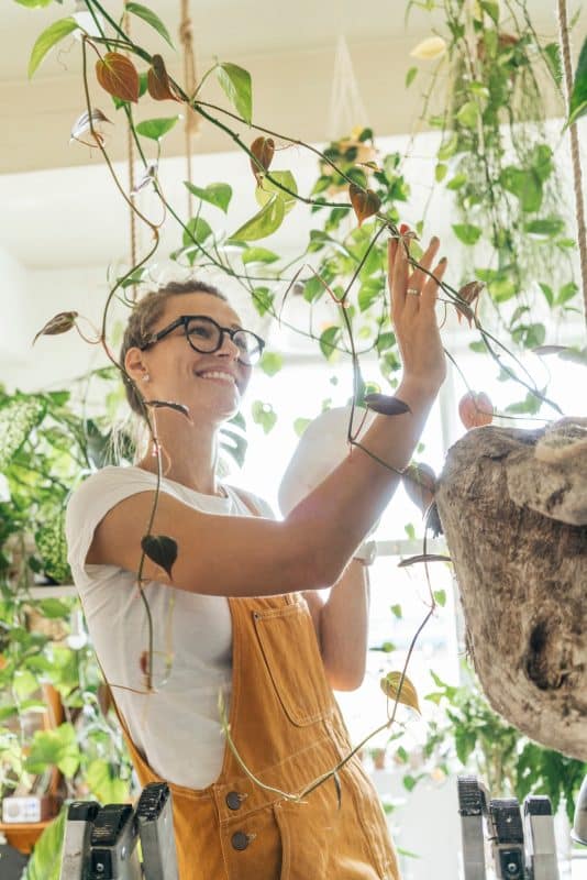 Smiling young woman caring for plants in a small shop