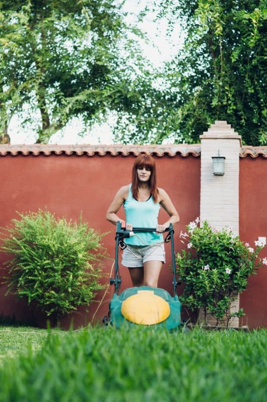 woman using a lawn mower in a garden