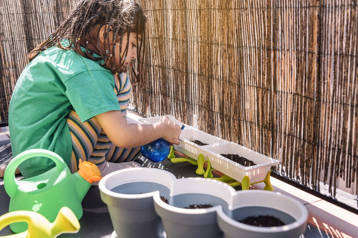 Kid at the balcony watering plants with a spray.jpg