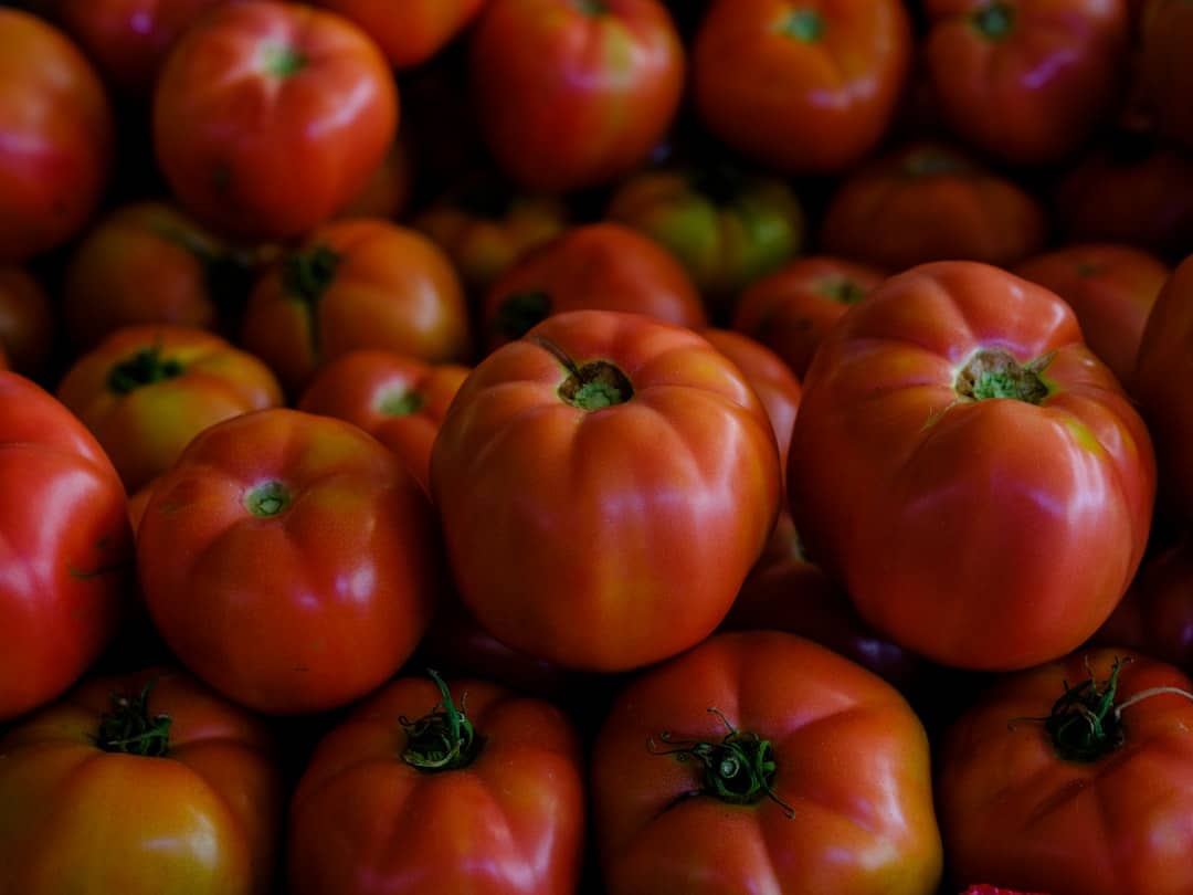 a pile of red and yellow tomatoes sitting on top of each other