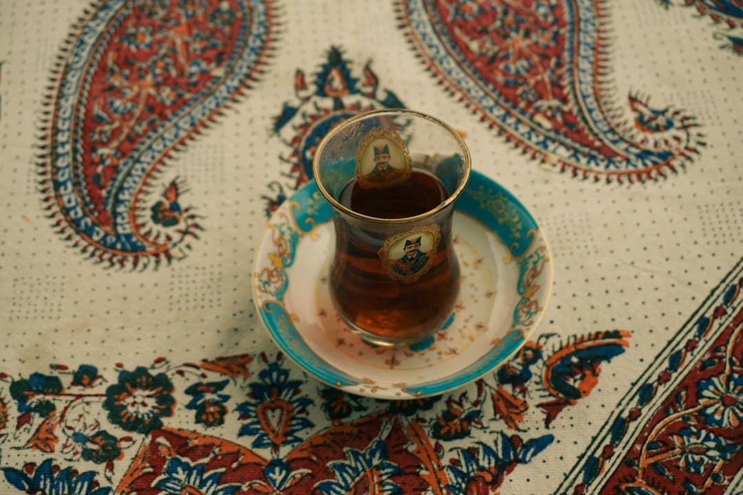A glass of tea on a patterned tablecloth.
